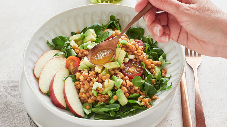 Pouring dressing over salad with spoon