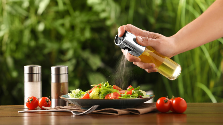 Person spraying DIY cooking spray on salad