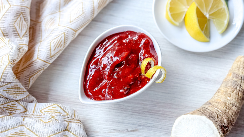 Scandinavian-inspired lingonberry cocktail sauce in serving dish with lemon twist and horseradish root