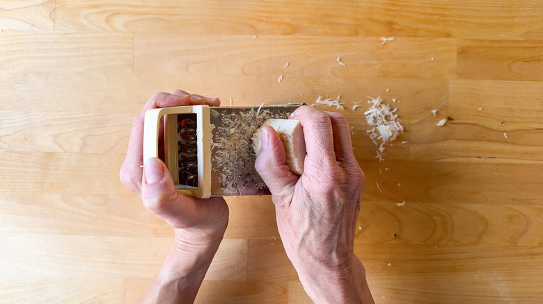 Grating horseradish root on cutting board