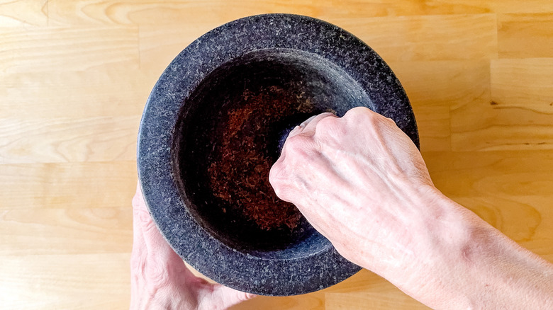 Grinding caraway seeds with mortar and pestle