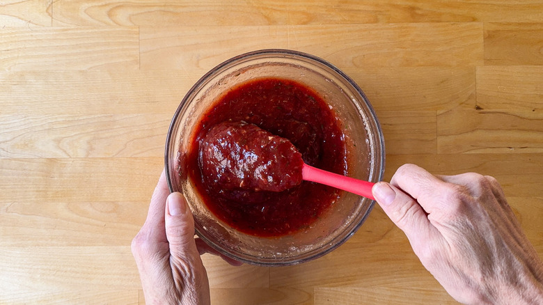 Mixing lingonberry cocktail sauce in glass bowl with rubber spatula