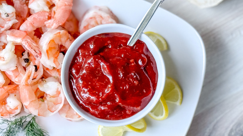 Scandinavian-inspired lingonberry cocktail sauce in bowl on platter with chilled shrimp and lemons