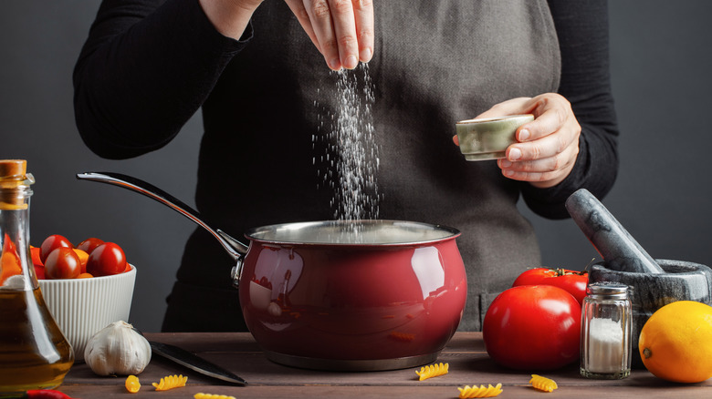 chef adding salt to pot