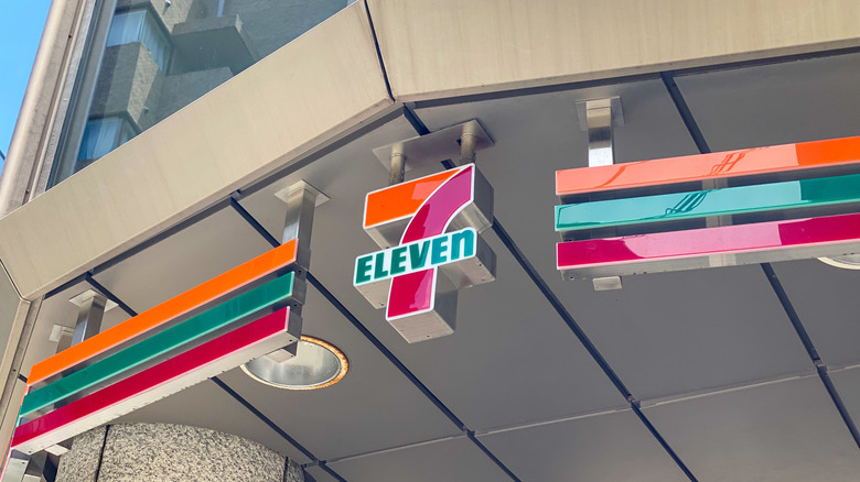 A 7-Eleven sign suspended from the ceiling outside of a store