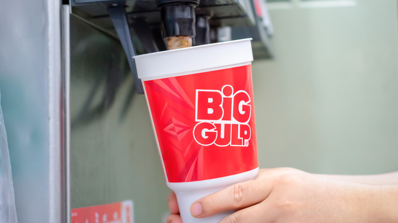 A person fills a Big Gulp cup from a soda dispenser