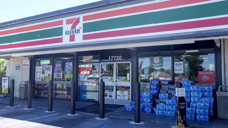 The exterior of a 7-Eleven with cases of water stacked outside