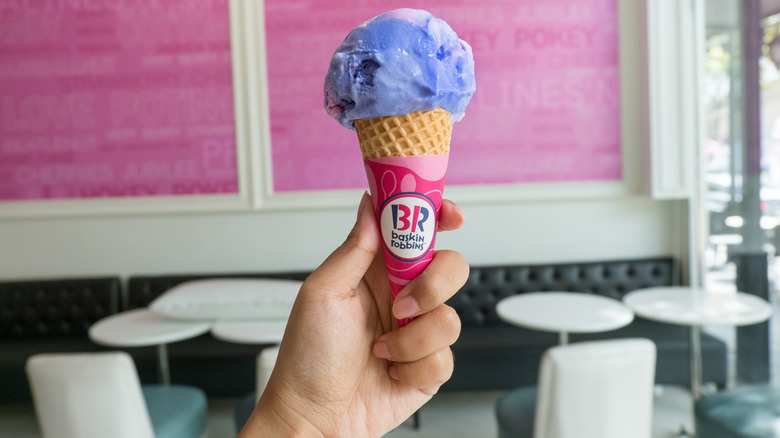 In a Baskin-Robbins parlor a hand holds a cone of the company's Cotton Candy ice cream