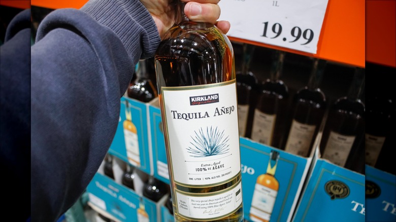 Person holding a bottle of Kirkland Tequila Añejo 