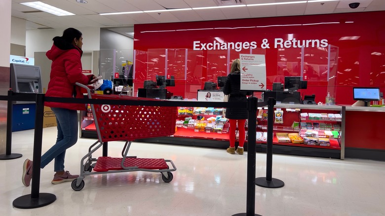 A woman in a red coat waits in line at the service counter at Target