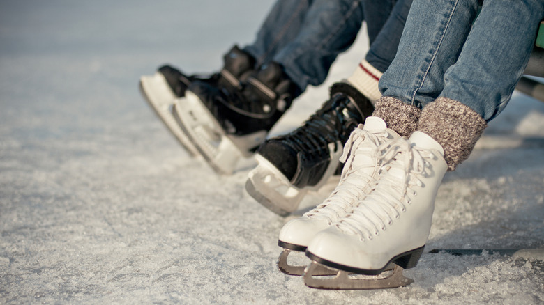 Three people wearing jeans with ice skates ready to go ice skating