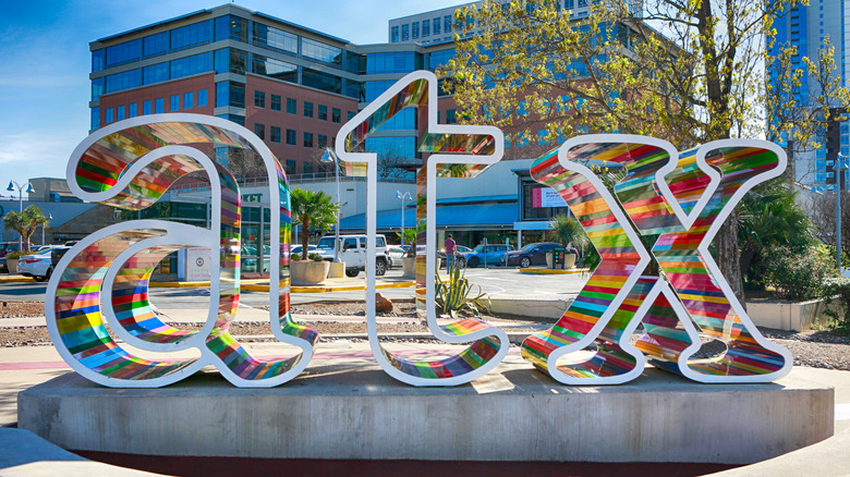 A colorful sign for Austin, Texas that reads "atx" in front of the original Whole Foods Market location