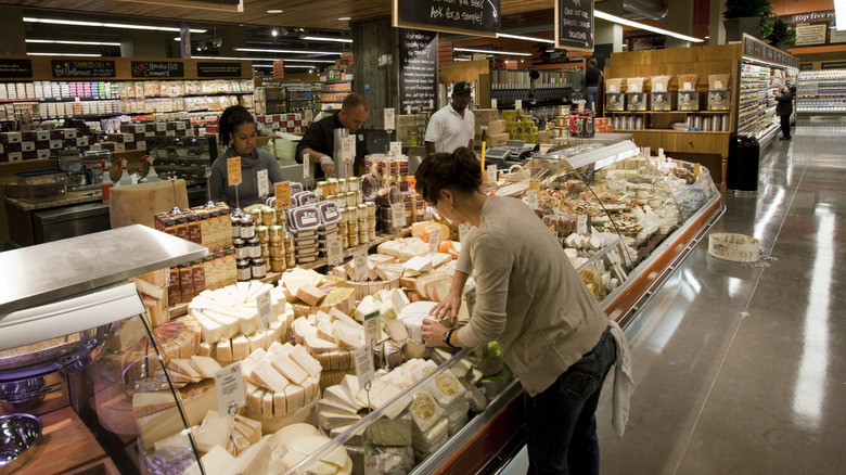 A woman looks through the selection of cheeses in the display case at Whole Foods Market