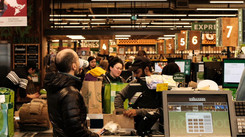 The checkout at Whole Foods with employees bagging groceries in paper bags