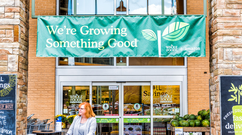 A woman leaving the Whole Foods store with a green banner over the entrance