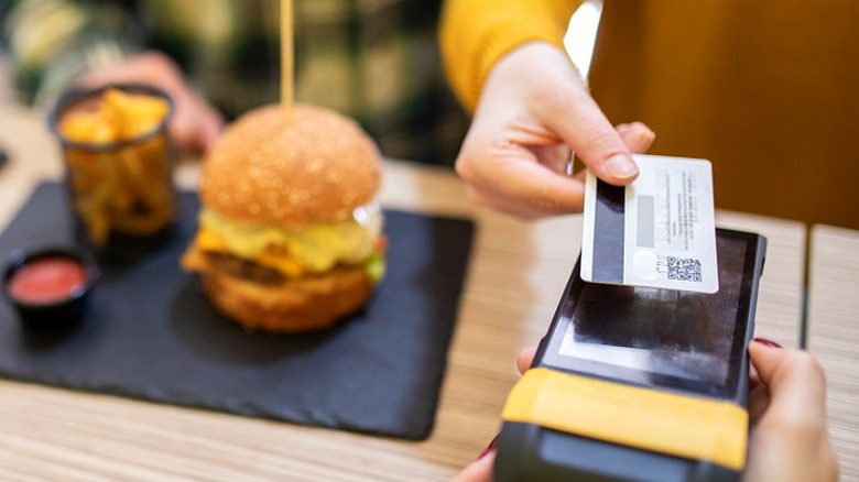 Person tapping card to pay for fast food tray