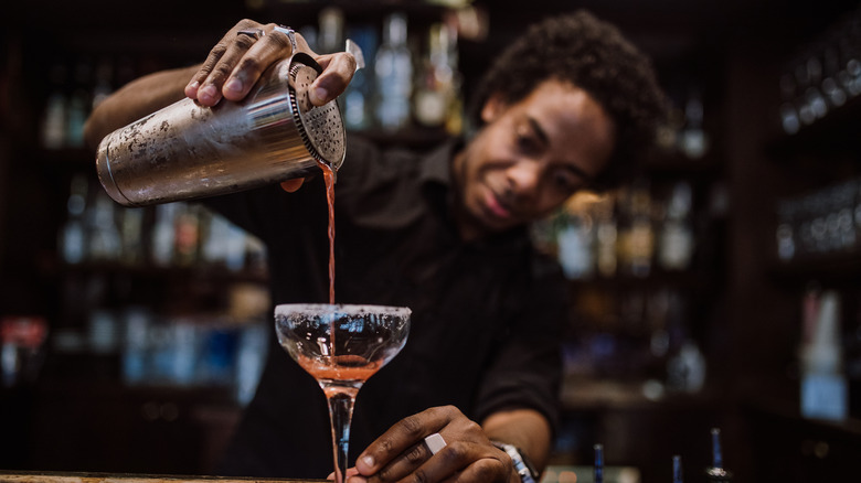 Bartender pouring cocktail from shaker 