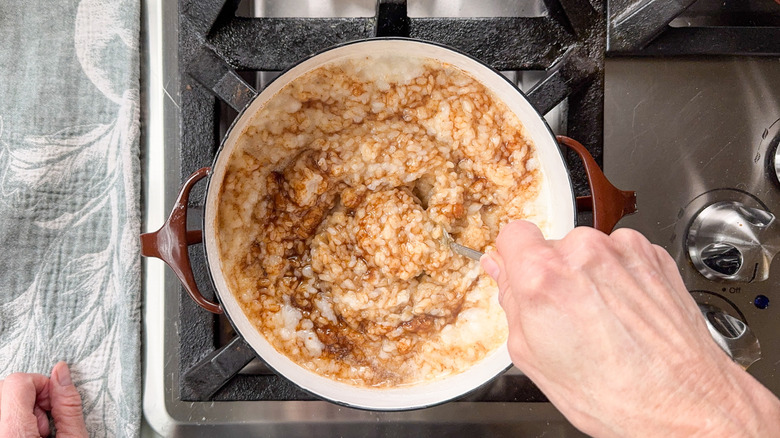 Stirring coconut sugar into sticky rice in pot on stovetop