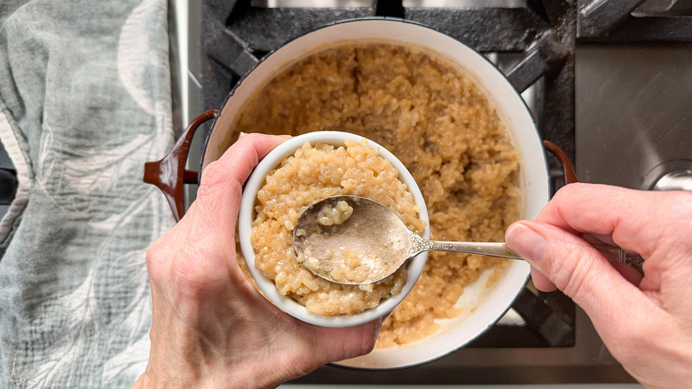 Packing sticky rice into a ramekin with a spoon