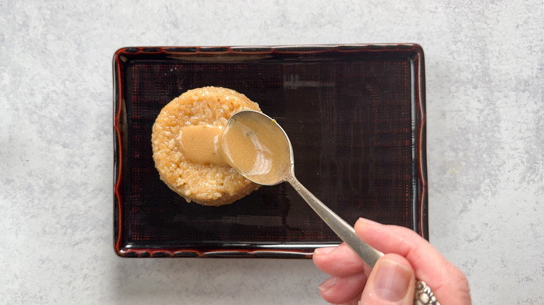 Spooning coconut milk sauce over sticky rice on plate