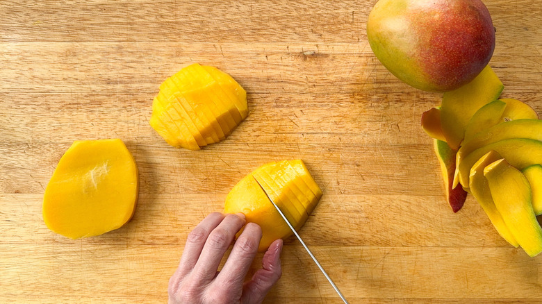 Slicing peeled mangoes on cutting board