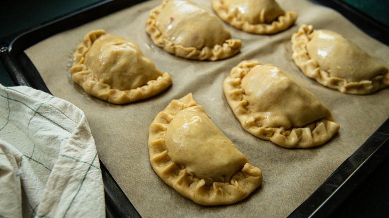 Uncooked empanadas on a baking sheet