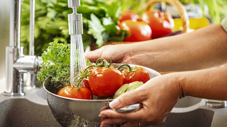 hands washing vegetables in a strainer