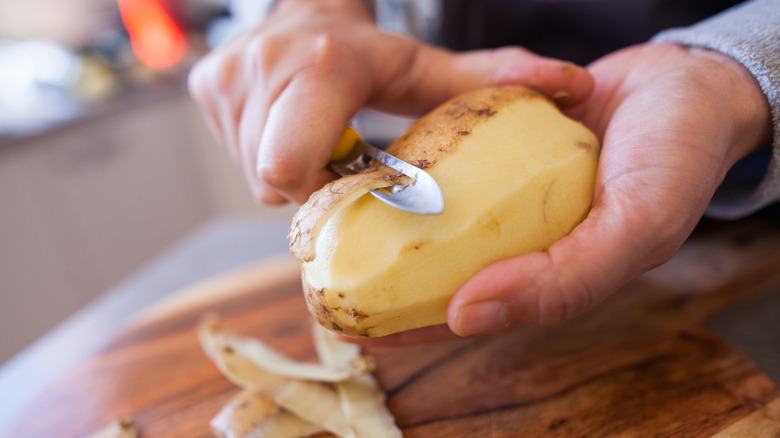 person peeling a potato