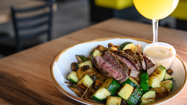 steak on a plate of fried vegetables with sauce