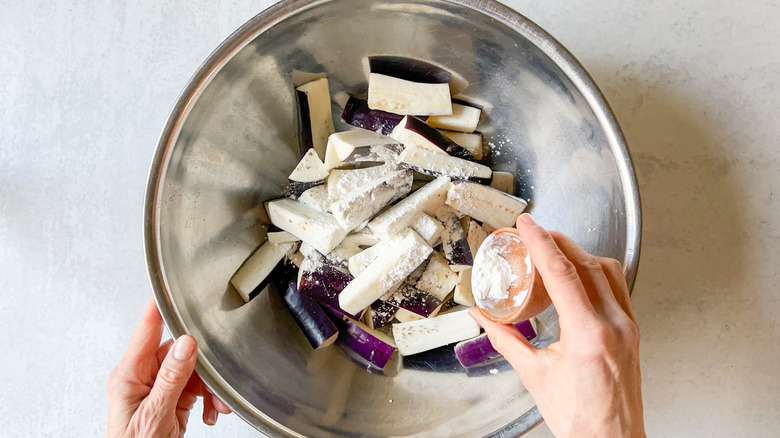 Tossing sliced Chinese eggplant with cornstarch in bowl