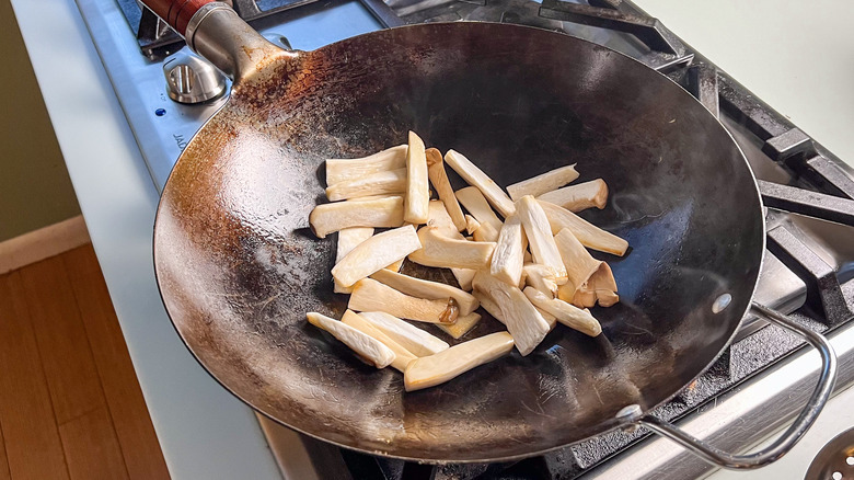Sliced oyster mushrooms in wok on stove
