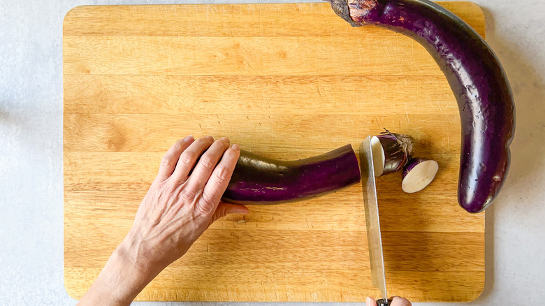 Trimming ends of Chinese eggplants on cutting board