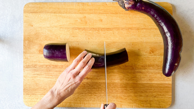 Cutting Chinese eggplant into sections on cutting board
