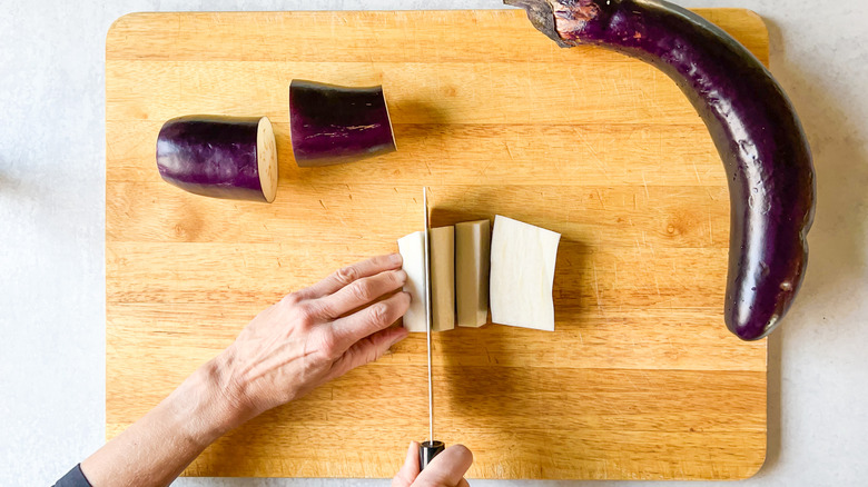 Cutting Chinese eggplant sections into strips on cutting board