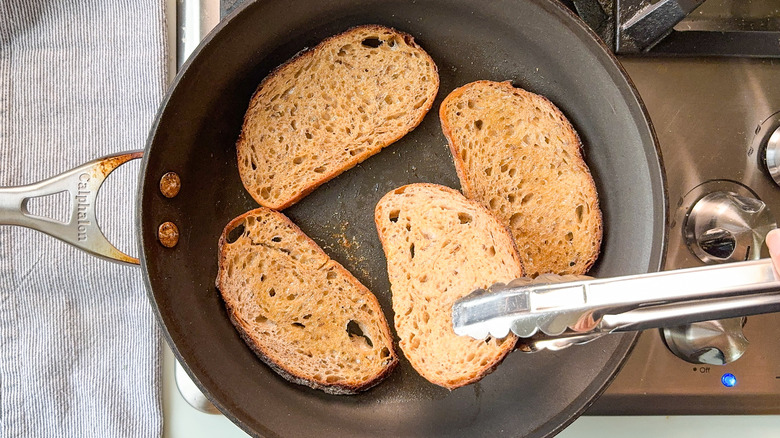 Turning rye bread slices in skillet with tongs