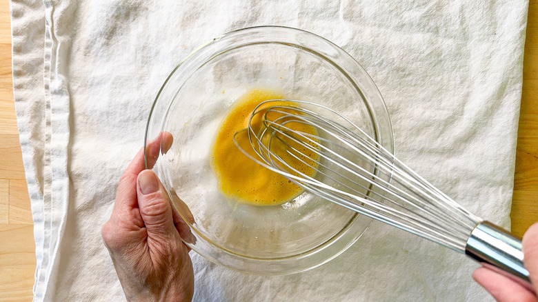 Whisking mayonnaise ingredients together in glass bowl