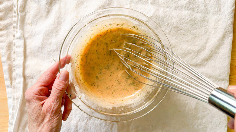 Whisking seasonings into mayonnaise from scratch in glass bowl