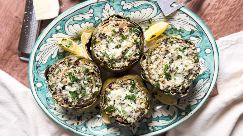 Sicilian-style stuffed artichokes on platter with cheese and grater