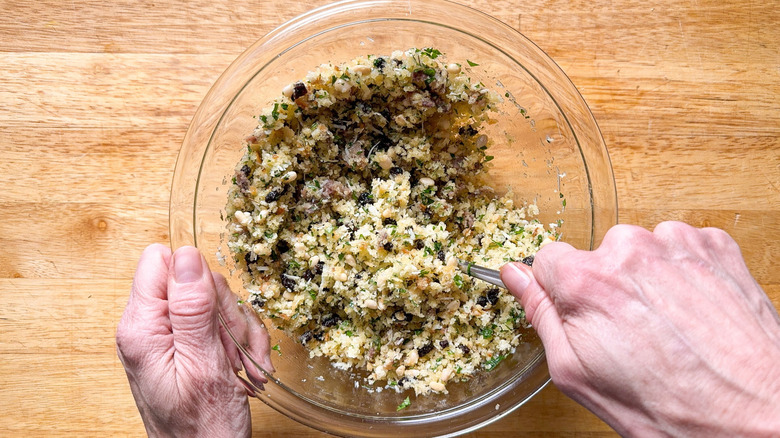 Mixing breadcrumb stuffing for Sicilian-style stuffed artichokes in glass bowl