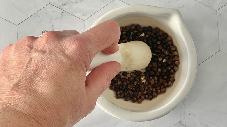 crushing peppercorns with pestle