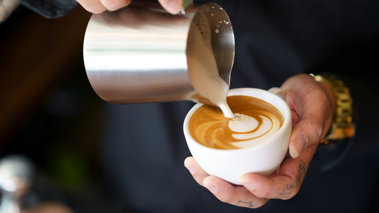 Barista pouring milk into a latte