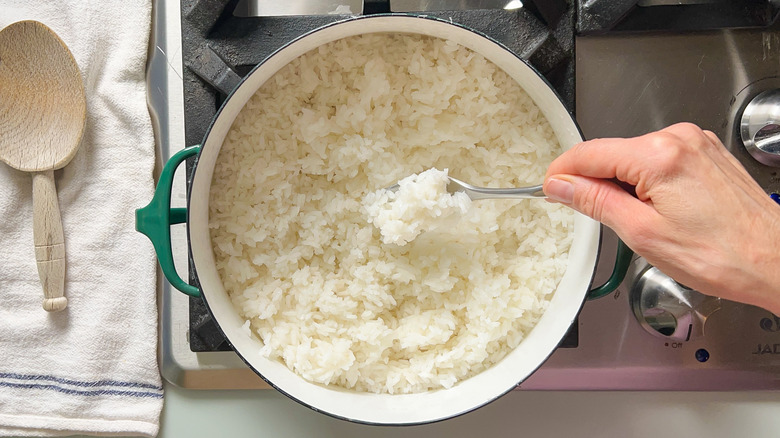 Fluffing cooked white rice in pot