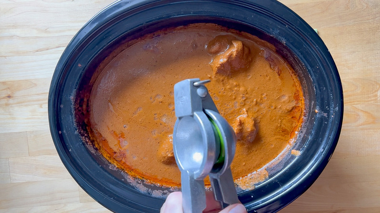Squeezing lime juice into chicken mole in slow cooker