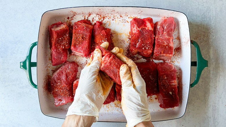 Coating beef short ribs with dry rub in pan