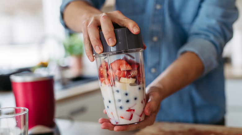 man preparing smoothie in blender