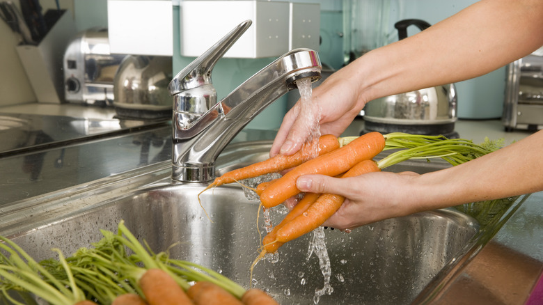 Person washing carrots in sink