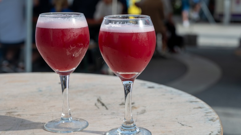 Two glasses of red lambic sour beers on a patio table