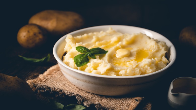 bowl of mashed potatoes with butter and basil leaf