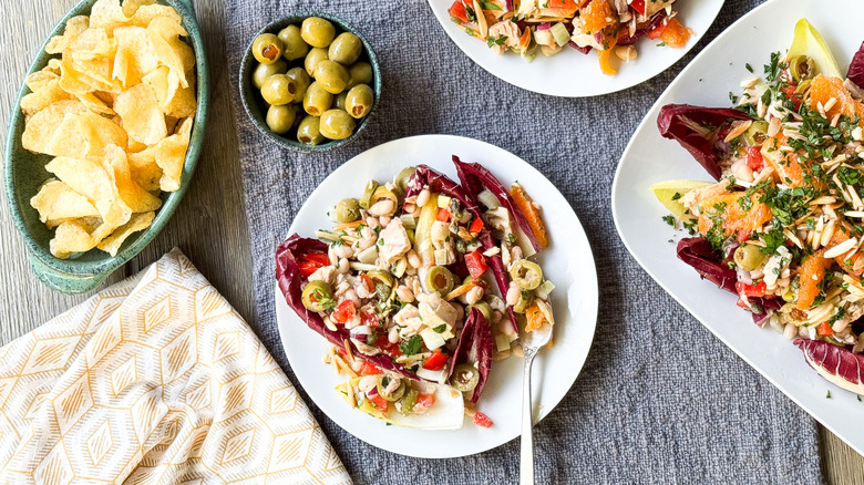 Spanish-inspired tuna salad with white beans and oranges on plates and platter with olives and potato chips