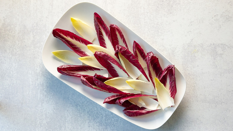 Red and white Belgian endive leaves on white platter